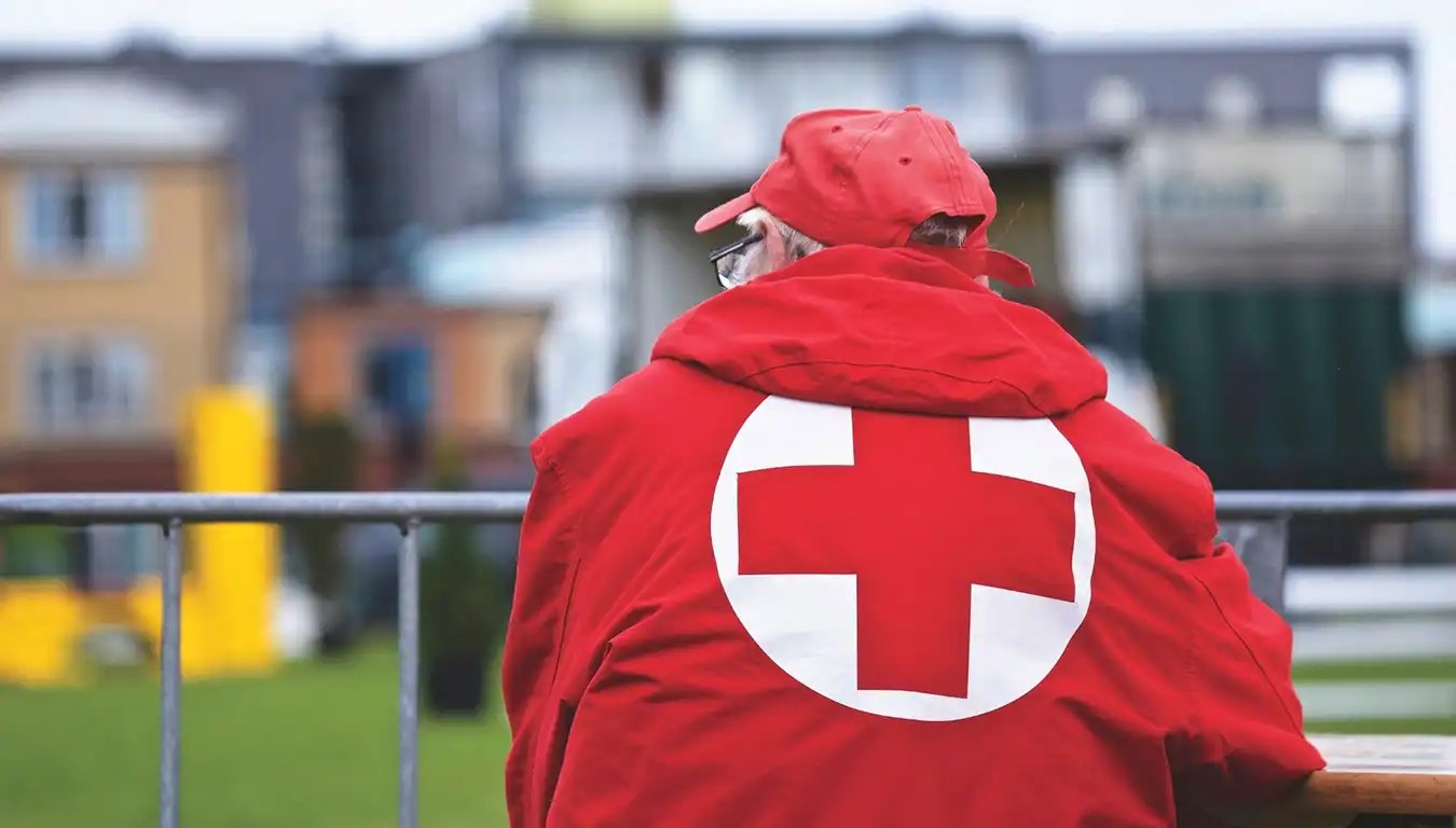 Mann har på jakke med røde kors logo på